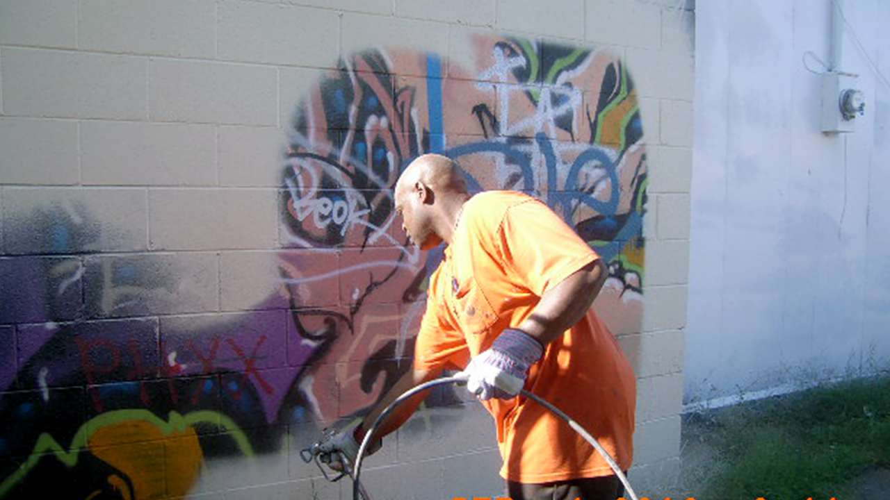 Worker painting over graffiti