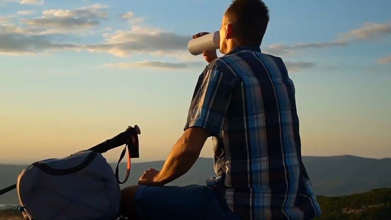 Man drinks water on a trail at sunset in a Phoenix Park