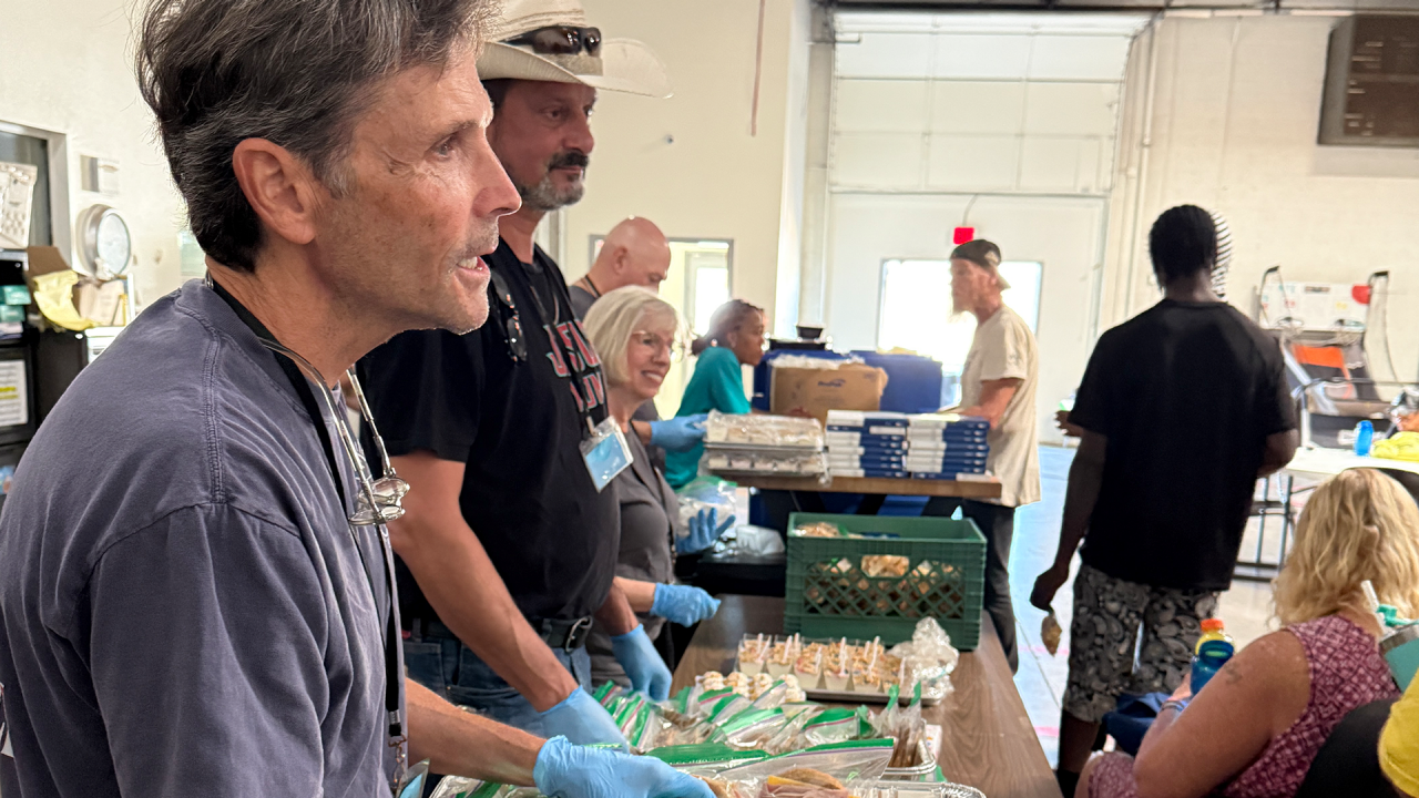 Volunteers serve a meal to unhoused people.