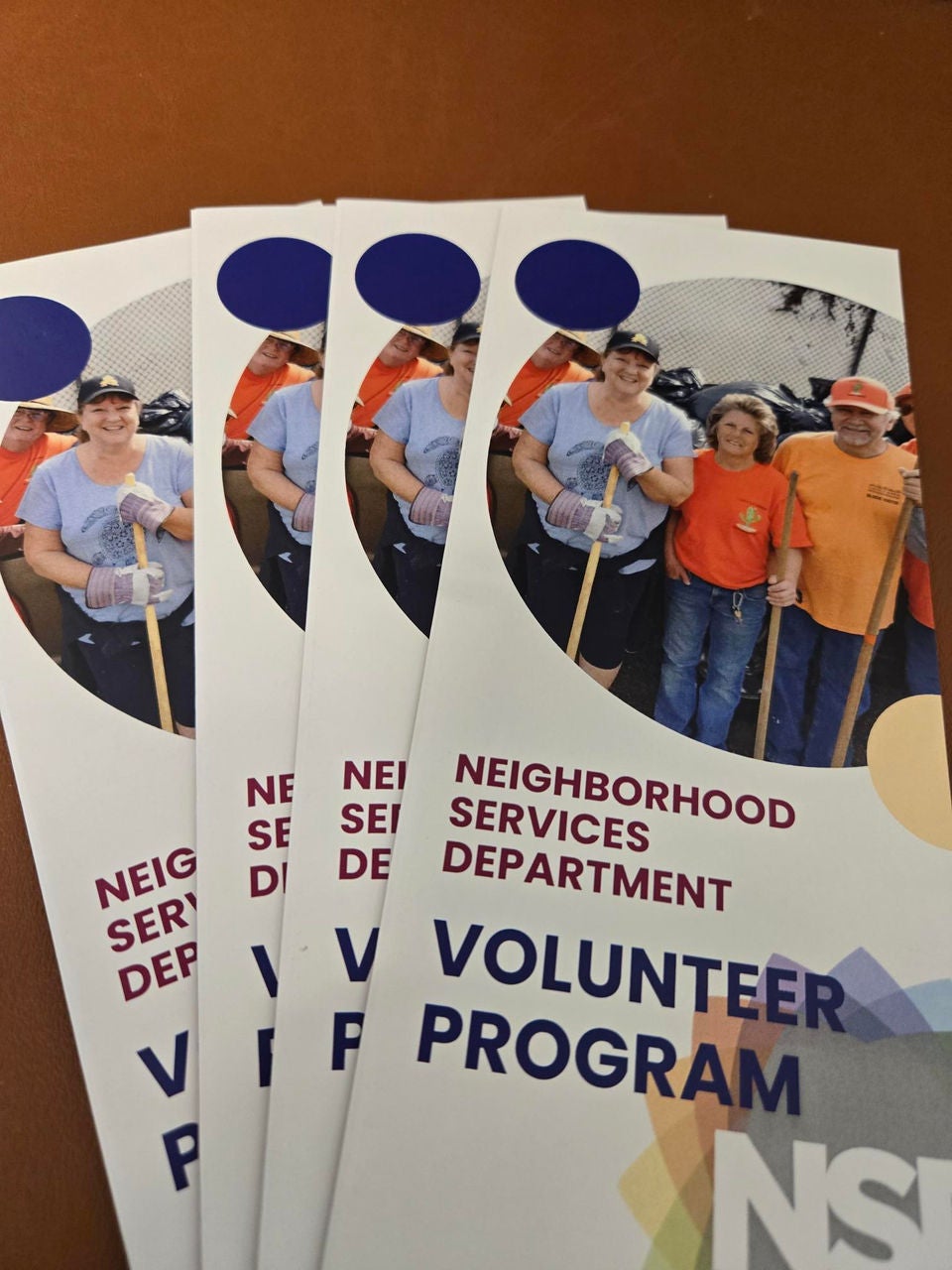 Four tri-fold brochures for the Neighborhood Services Department's Volunteer Program featuring a photo of adult volunteers holding cleanup tools.
