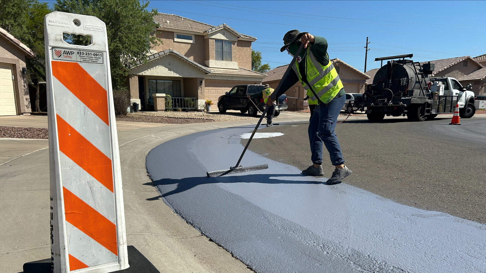 Worker in road applying Cool Pavement to roadway. 