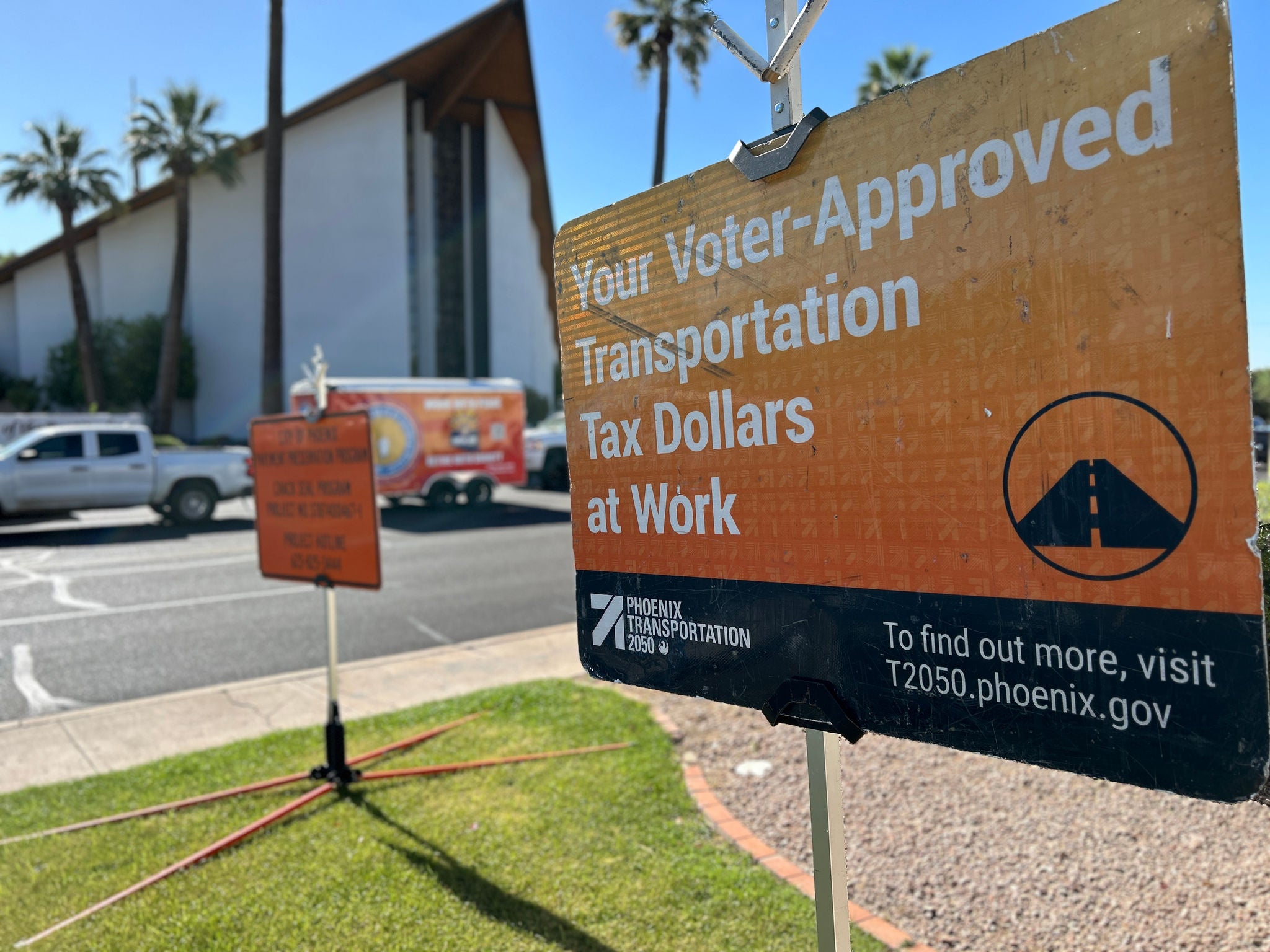 An orange sign in foreground with words: "Your Voter-Approved Transportation Tax Dollars at Work." 