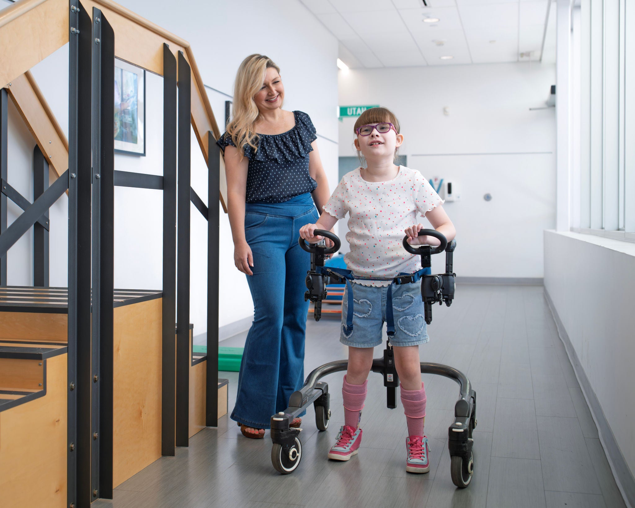 a girl walks with accessible device while women stands nearby and watches