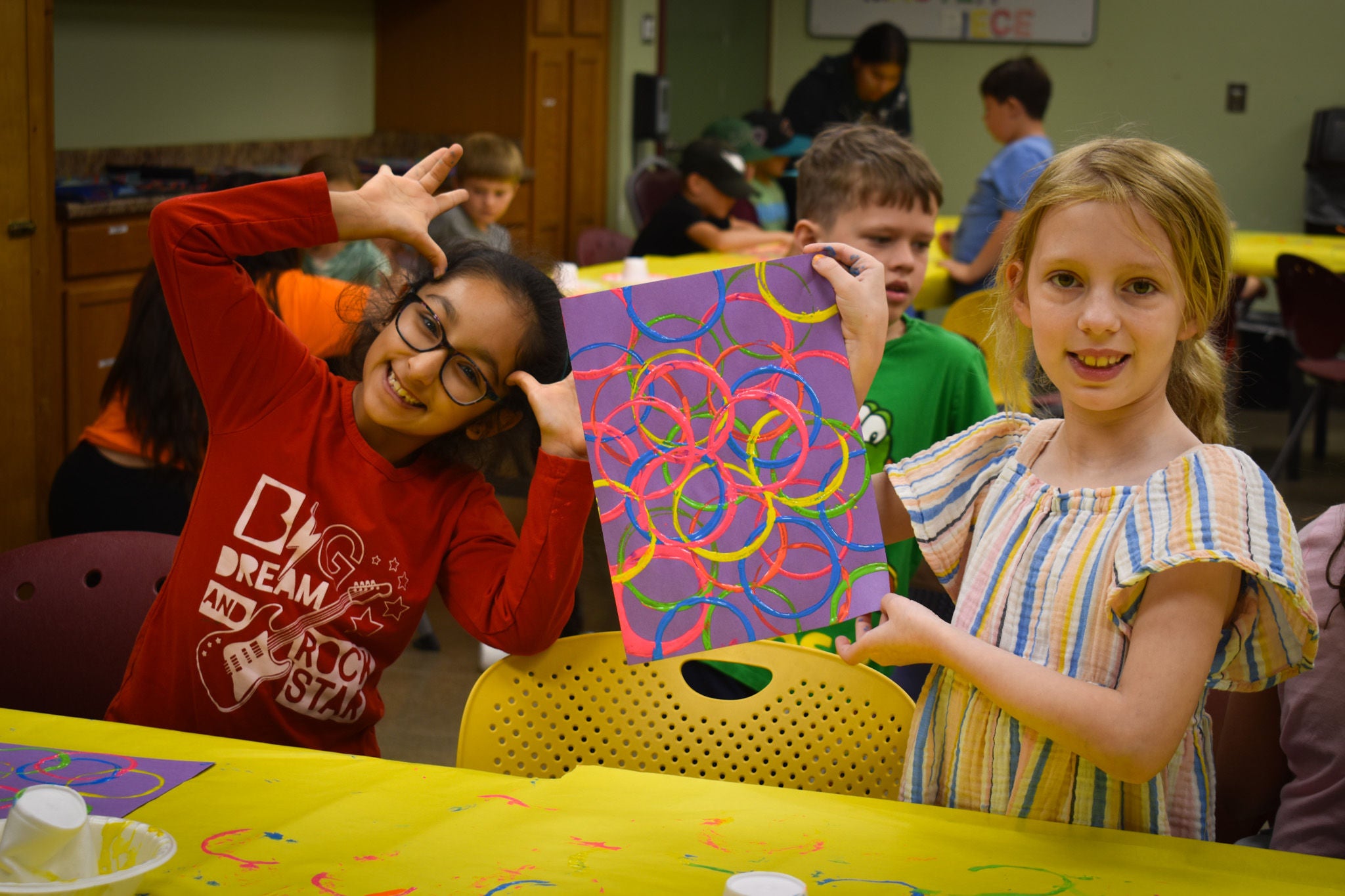 Two children posing with art project and smiling.