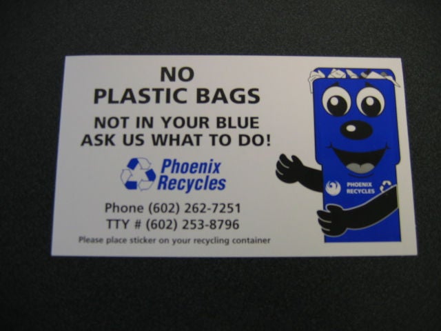A sticker that features Binny, a cartoon mascot in the shape of a curbisde bin with arms and legs. The sticker reads, "No Plastic Bags. Not in your blue -- ask us what to do! Phoenix Recycles"