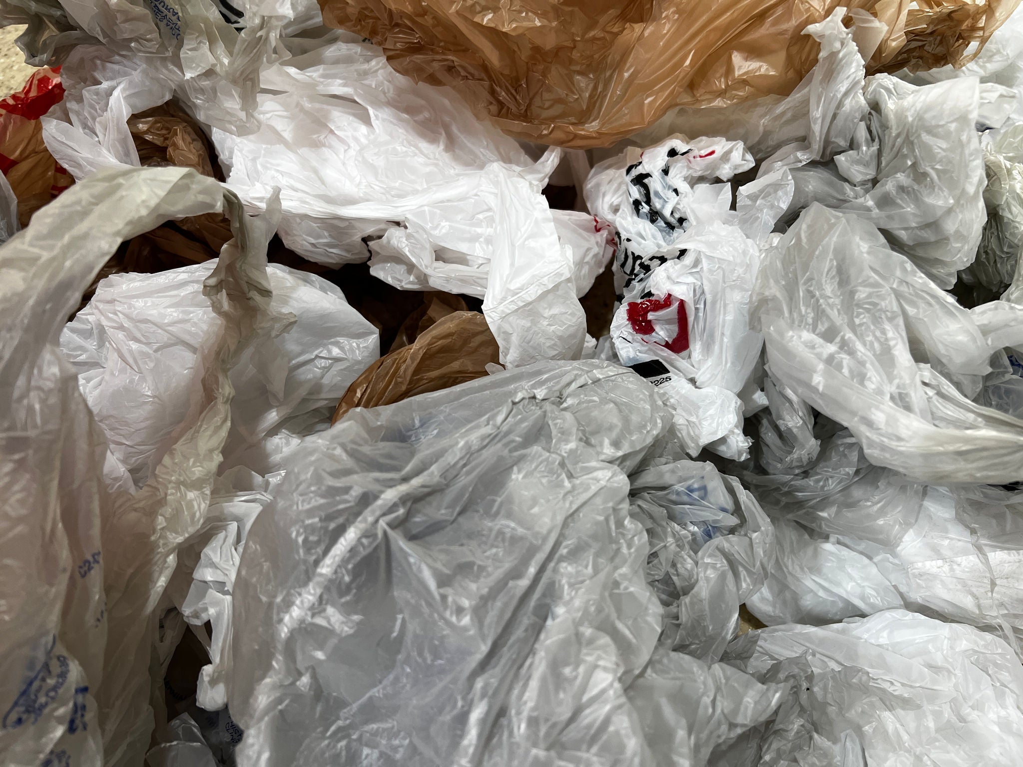 A tight shot of dozens of crumpled, plastic grocery bags of various colors