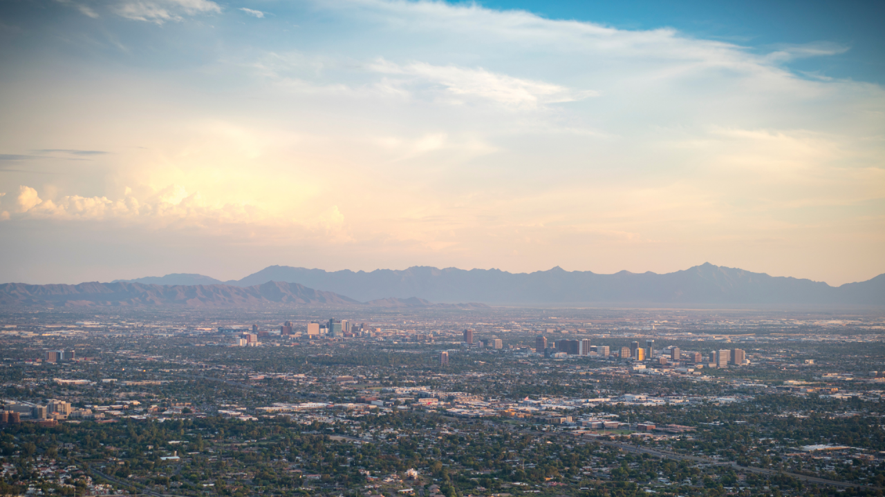 City of Phoenix skyline view with downtown buildings in foreground and mountains in background on a sunny but cloudy day