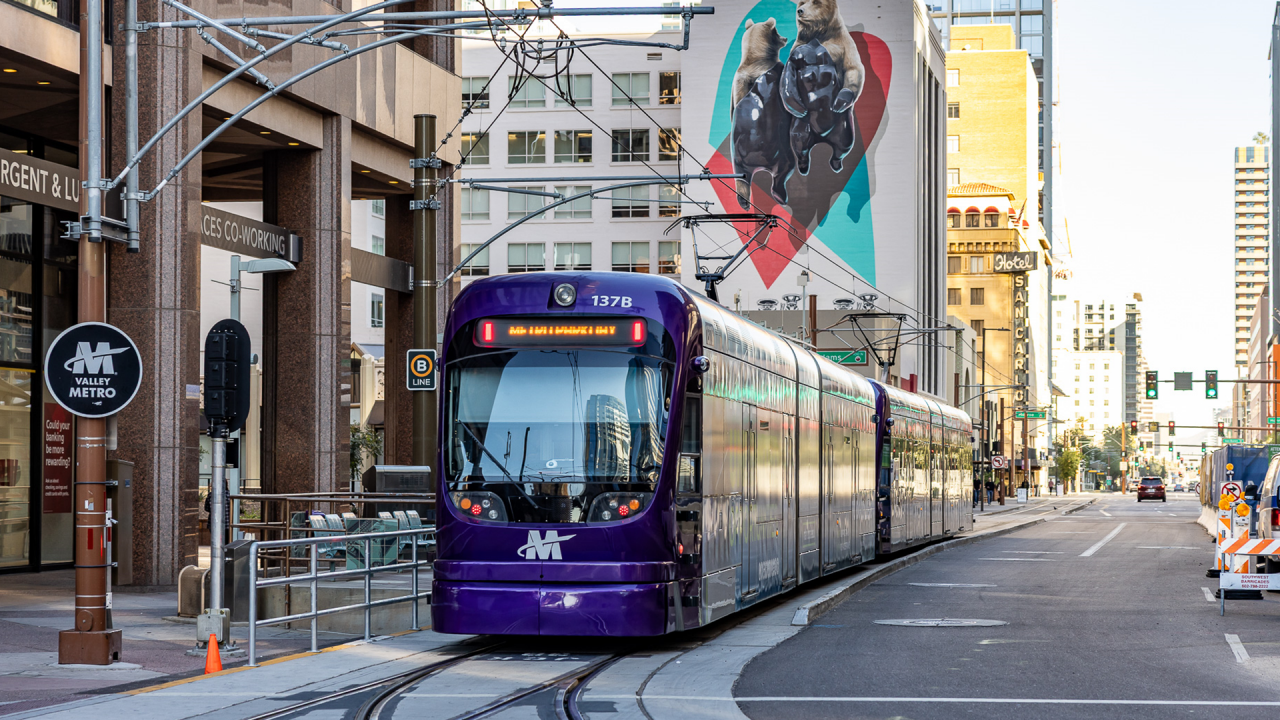Image of a purple Valley Metro light rail travel through Downtown Phoenix. 