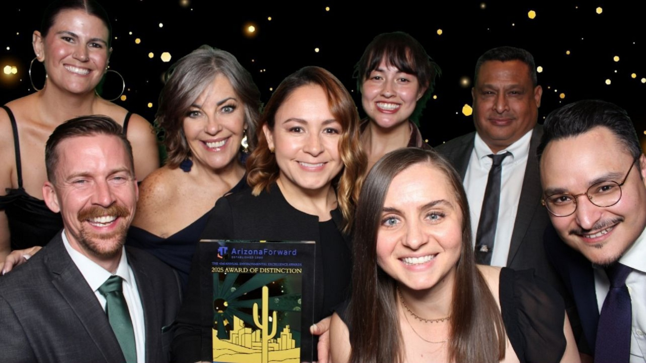 8 people in formal wear gather around a trophy and smile